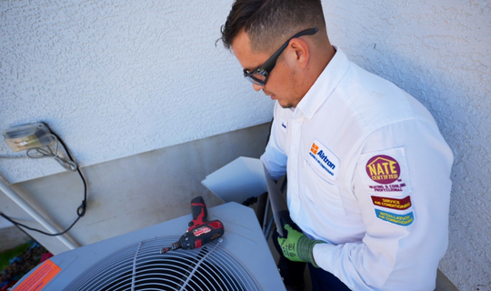 Air conditioning installation technician working on outdoor AC unit