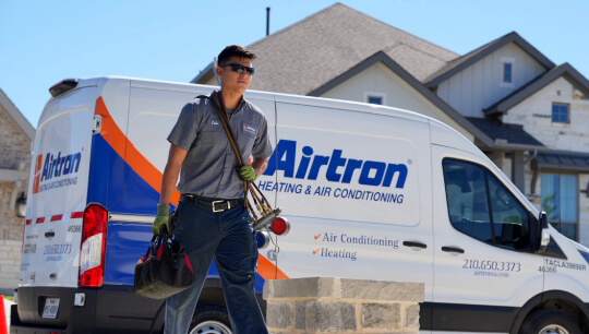 Airtron technician with tools next to service van at residential home