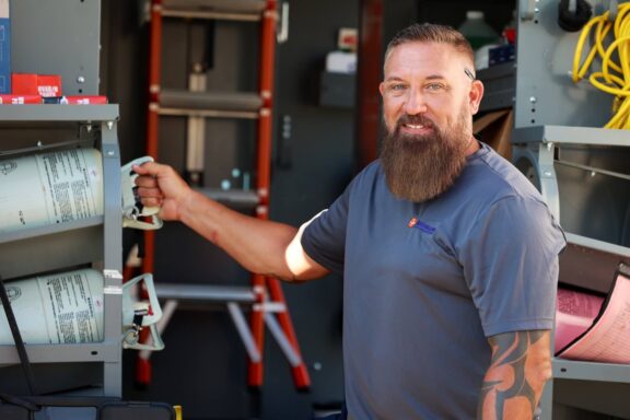 Airtron HVAC technician with beard organizing equipment in service van