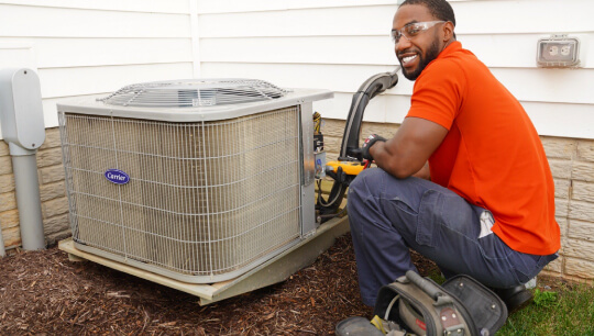 HVAC technician installing Carrier outdoor air conditioning unit