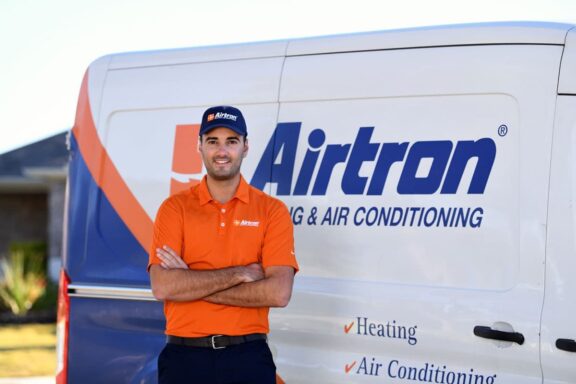 Airtron Austin HVAC technician standing in front of a van with an Airtron Heating & Air Conditioning logo